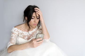 sad and worried bride with mobile phone in the hand
