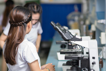 Young scientist working with microscope in a laboratory. Young scientist doing research.