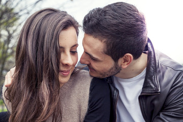 nice couple of boyfriends embraces and kisses on a wooden bridge