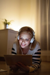 Woman lying on the floor, working on tablet at night.