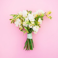 Wedding bouquet of white flowers on pink background. Flat lay, top view. Beauty background.