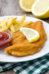Wiener schnitzel with fried potatoes on wooden background

