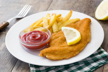 Wiener schnitzel with fried potatoes on wooden background

