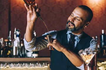 Barman is making cocktail at night club.