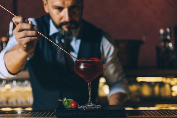 Barman is making cocktail at night club.