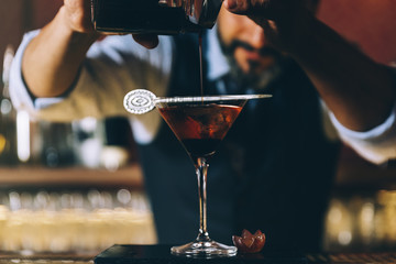 Barman is making cocktail at night club.