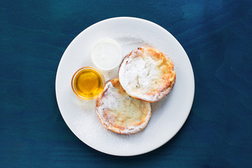 Cottage cheese pancakes with honey on blue wooden background