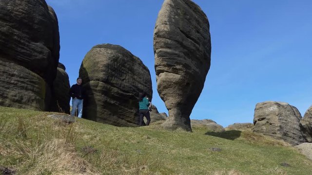 Couple, man and woman, both wearing glasses walking by the Bride Stones near Todmorden, West Yorkshire, England