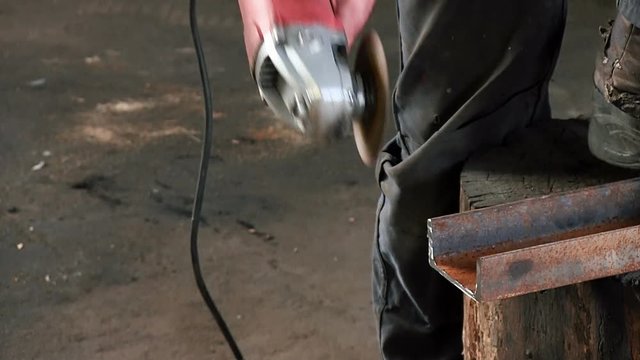 A man cuts a rusty metal beam, using a circular turbine. Angle Grinder red color slowmotion close-up Finished work sawing have sound audio