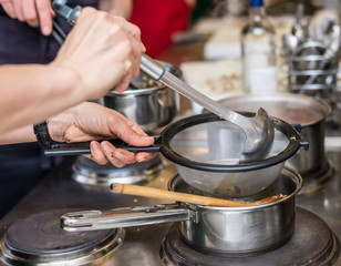 Woman in the kitchen cooking, mixing food in a pot.