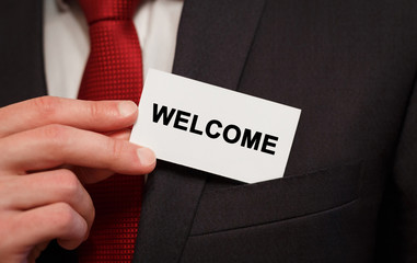 Businessman putting a card with text WELCOME in the pocket