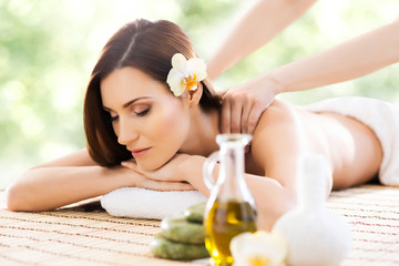 Obraz na płótnie Canvas Young and beautiful girl relaxing in spa salon. Massage therapy over seasonal summer or spring background. Healing medicine and health care concept.