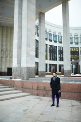 Wide shot of handsome Middle-Eastern man standing among modern city architecture