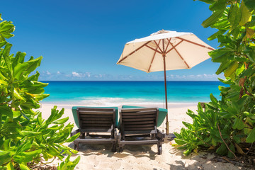 Paradise beach with umbrella and beach chairs.