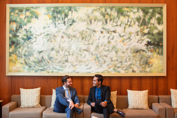 Two Smiling Business Men Chatting in Lounge