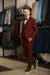 Handsome young bearded businessman in classic suit. A young stylish man in a jacket. It is in the showroom, trying on clothes, posing. Advertising photo