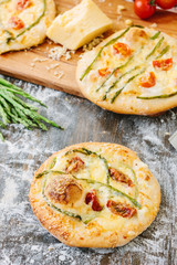 Mini pizza with asparagus. Traditional small pizza for personal eating filling with cheese, tomatoes and asparagus.