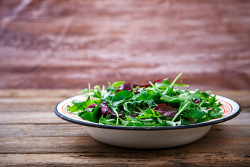 Fresh Green Mix Salad on Vintage Wooden background in a metal bowl.Leaves Of Spinach,Arugula,Romaine,Lettuce.Concept of Healthy Food.Vegetarian.Copy space for Text. selective focus.
