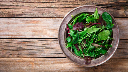 Fresh Green Mix Salad on Vintage Wooden background in a metal bowl.Leaves Of Spinach,Arugula,Romaine,Lettuce.Concept of Healthy Food.Vegetarian.Copy space for Text. selective focus.