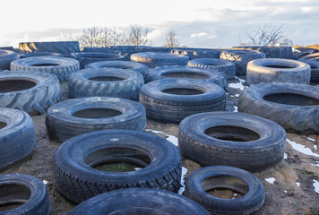 The old rubber tyre from a tractor and a car , laid on the silo . Serve as a load restraint top membrane covering the silage mixture . Dairy farm in Podlasie, Poland.