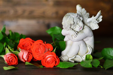 Angel guardian and roses on wooden background