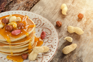 Stack of hot pancakes with nuts and caramel syrup.