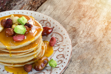 Stack of hot pancakes with nuts, dried fruits and caramel syrup.