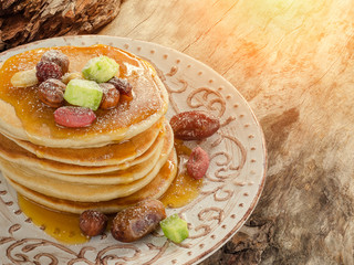 Stack of hot pancakes with nuts, dried fruits and caramel syrup.