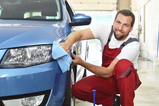 professionelle Autoreinigung in einer Werkstatt - Mann poliert Lack eines Fahrzeuges // Professional car cleaning in a workshop - man polishing paint of a vehicle