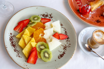 Slices of kiwi, pineapple, orange, strawberry - fruit dessert on the plate.