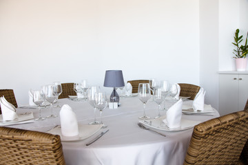 The wine glasses stands on a round table covered with a white tablecloth