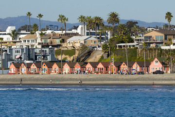 Fototapeta na wymiar A row of identical beach side cottages as viewed from a pier out in the ocean.