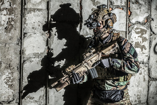 Army Ranger moving along the concrete wall with his black shadow
