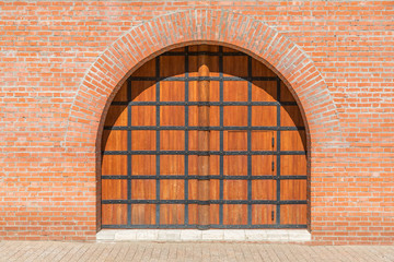 . A wooden gate with a door in the brick wall. Space to insert text.