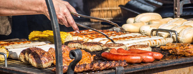 Grillfest: Frau bereitet Bratwürste und Steaks zu