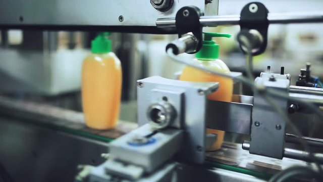 Packaging machine / process of packaging liquid soap in a modern factory / Line of packaging at a cosmetic plant / Plastic containers on a packaging line at a cosmetic factory / Industrial equipment