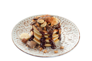 Stack of hot pancakes with nuts, bananas and chocolate syrup. Isolated