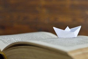 Paper boat on the old book