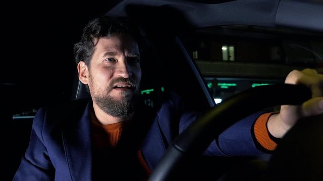 Sad man driving car at night in city feelin lonely