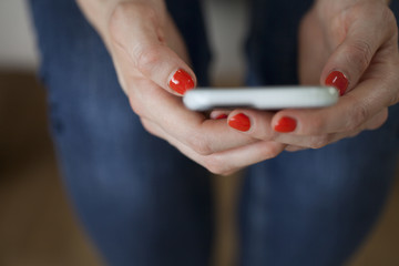 Woman holding Smartphone with Coral Nails
