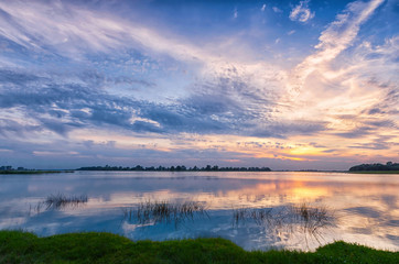 Nature background sunset over the river and beautiful sky with reflection in the water.