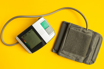 Digital instrument for measuring blood pressure on a yellow background.