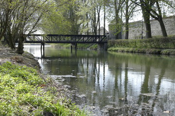 Fototapeta na wymiar bridge in a city park recletced in a lake