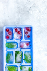 Obraz na płótnie Canvas Ice cubes with berries and mint stone background top view mock up