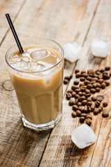 cold coffee glass with ice cubes on wooden table background