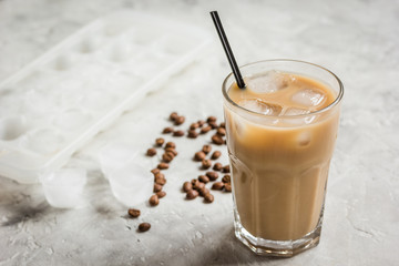 cold coffee glass with ice cubes on stone table background