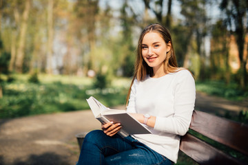 Obraz premium college student reading a book in park sitting on bench