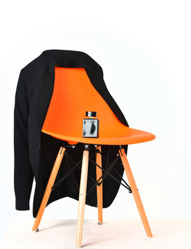 Orange plastic office chair with black jacket and perfume bottle