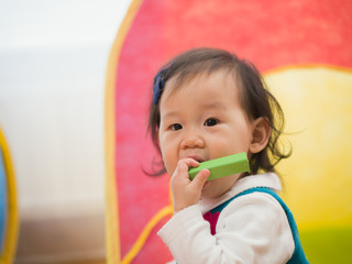 teething baby girl playing toy block