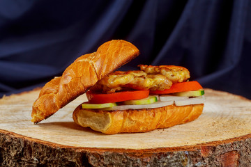 chicken sandwich with onion tomato cucumber on a wooden stand